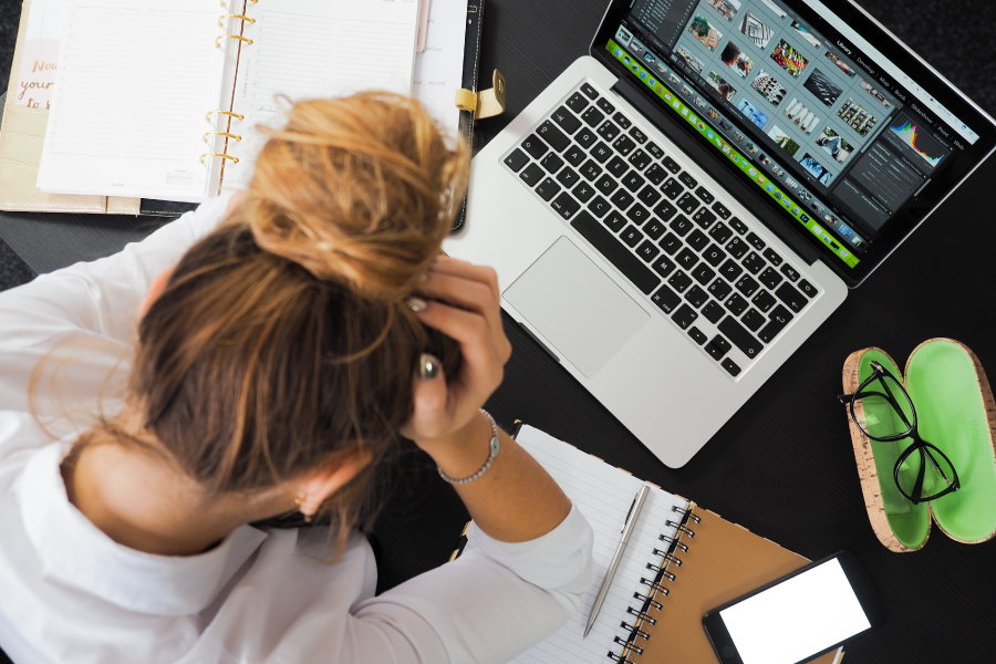 According to a 2021 study of 1,501 workers by the American Psychological Association, 79 percent reported having workplace stress | Young woman working on computer looks tired, frustrated, and burnt out.