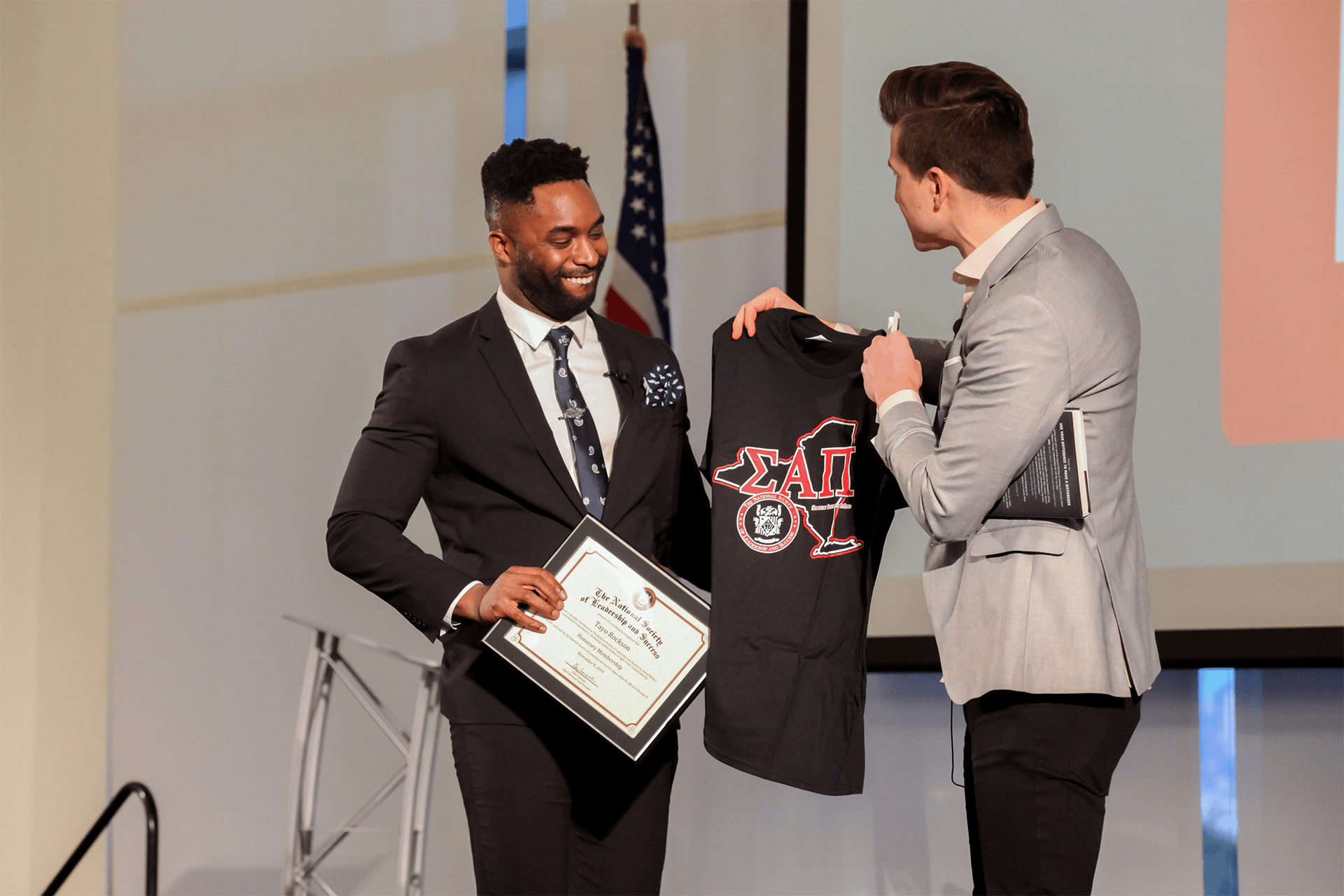 Excited NSLS student receiving a diploma and a t-shirt