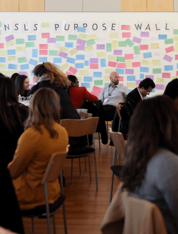 Group of NSLS members sitting around tables at a seminar